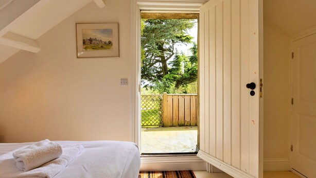 Un dormitorio con cama, una puerta que da a un balcón y un cuadro en la pared.