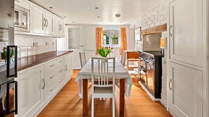 Una cocina moderna con armarios blancos, encimera de madera y una zona de comedor con mesa y sillas.