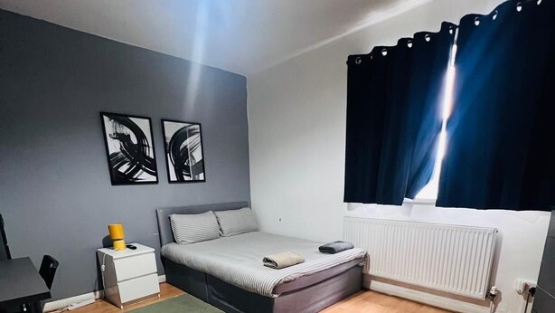 A bedroom with a bed, a desk, a radiator, and artwork on the wall. - London E1 Hostel (London)