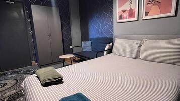 Une chambre d’hôtel avec un grand lit, un bureau, une chaise et une armoire.