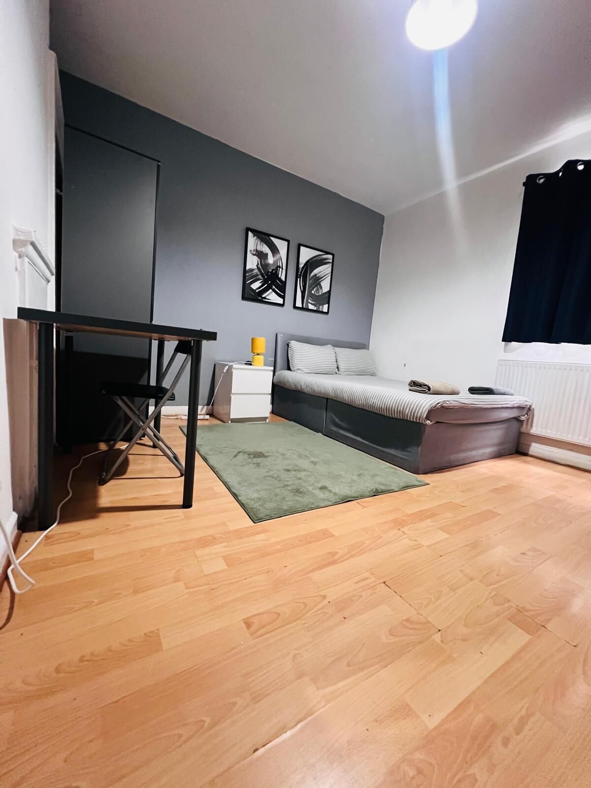 Une chambre moderne avec un lit, un bureau et un radiateur.