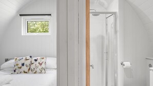 Ein Schlafzimmer mit Bett, Fenster und Duschbereich.