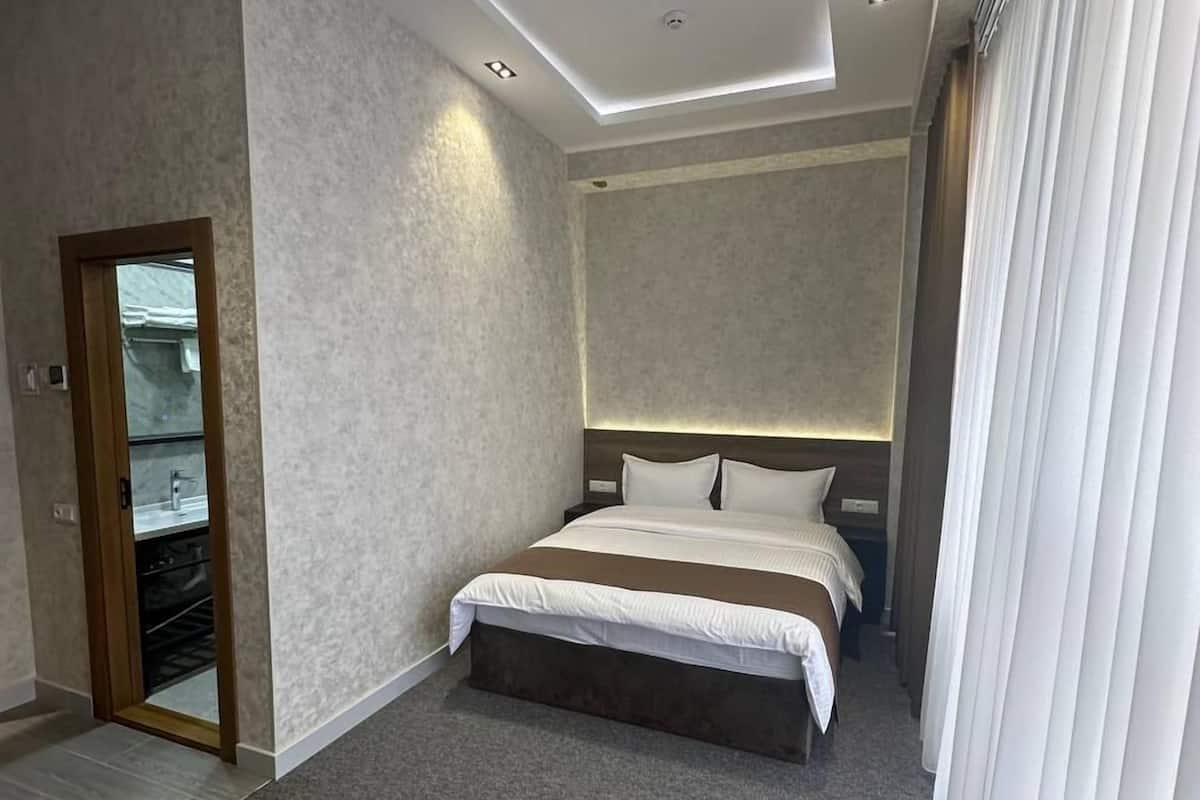 A modern hotel room with a large bed, a wooden table, and a walk-in closet.