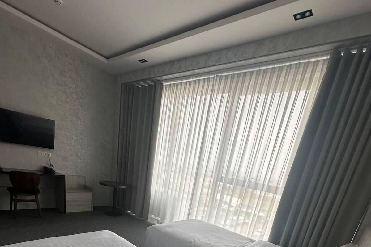 A hotel room with two beds, a desk, and a TV.
