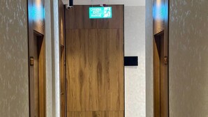 A hallway with wooden doors and a sign indicating an exit. - The loren hotel (Tashkent)