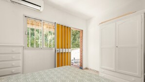 Een slaapkamer met een bed, een kledingkast, een raam met zonwering en een deur.