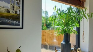 A kitchen with a wooden countertop, a bowl of green pears, a large potted plant, and a framed picture of King's College Cambridge. - Beautiful  villa for 4 guests with WIFI, TV and terrace (Sawston)