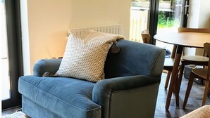 A living room with a blue sofa, a patterned throw pillow, and a painting on the wall. - Beautiful  villa for 4 guests with WIFI, TV and terrace (Sawston)