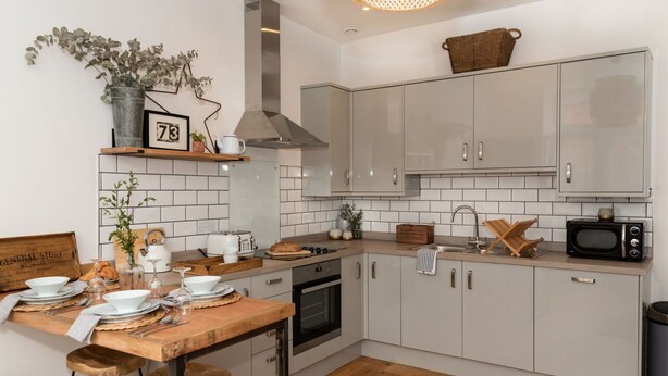 Une cuisine moderne avec des armoires blanches, un plan de travail en bois et un luminaire suspendu.