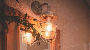 Un luminaire mural doté d’un cadre en métal et de panneaux en verre, fixé sur un mur à texture.
