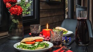 Una mesa de comedor dispuesta con una vela, una botella de vidrio y un plato de comida.
