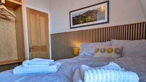 A bedroom with a bed, a wooden wardrobe, a framed picture on the wall, and a bedside lamp. - Nice apartment for 2 guests with WIFI and TV (Matlock)