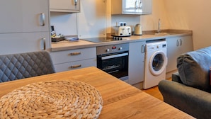 A compact kitchen with a stove, oven, microwave, and a washing machine. - Nice apartment for 2 guests with WIFI and TV (Matlock)