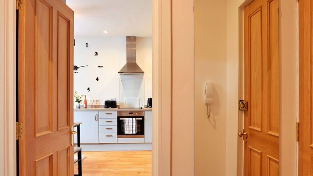 A modern kitchen with white cabinets, a stainless steel range hood, and a built-in oven.