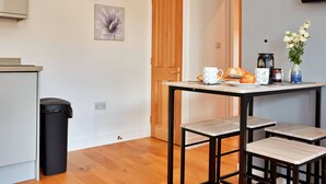A modern kitchen with a wooden table, chairs, and a coffee maker.
