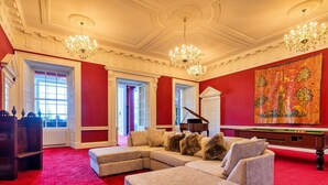 A grand room with a red carpet, a sectional sofa, a grand piano, and a large tapestry. - Beautiful  villa for 9 people with WIFI, TV, terrace and pets allowed (Hickleton)