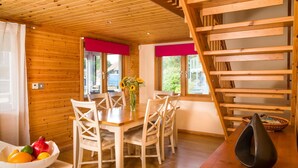 Ein Holzinterieur mit einem Esstisch, Stühlen, einer Obstschale und einer Treppe.