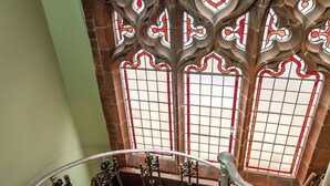A spiral staircase with ornate metal railings and stained glass windows with red and white patterns. - Beautiful  villa for 2 guests with pets allowed (Cromer)