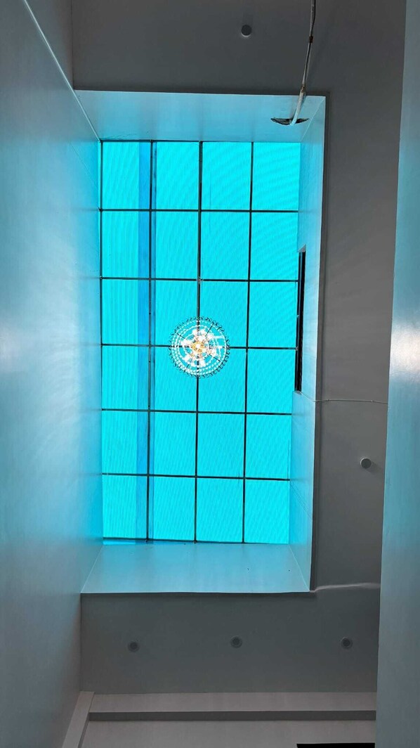 Una habitación con un ventanal grande dividido en varias secciones, un elemento decorativo central y un techo con iluminación empotrada.