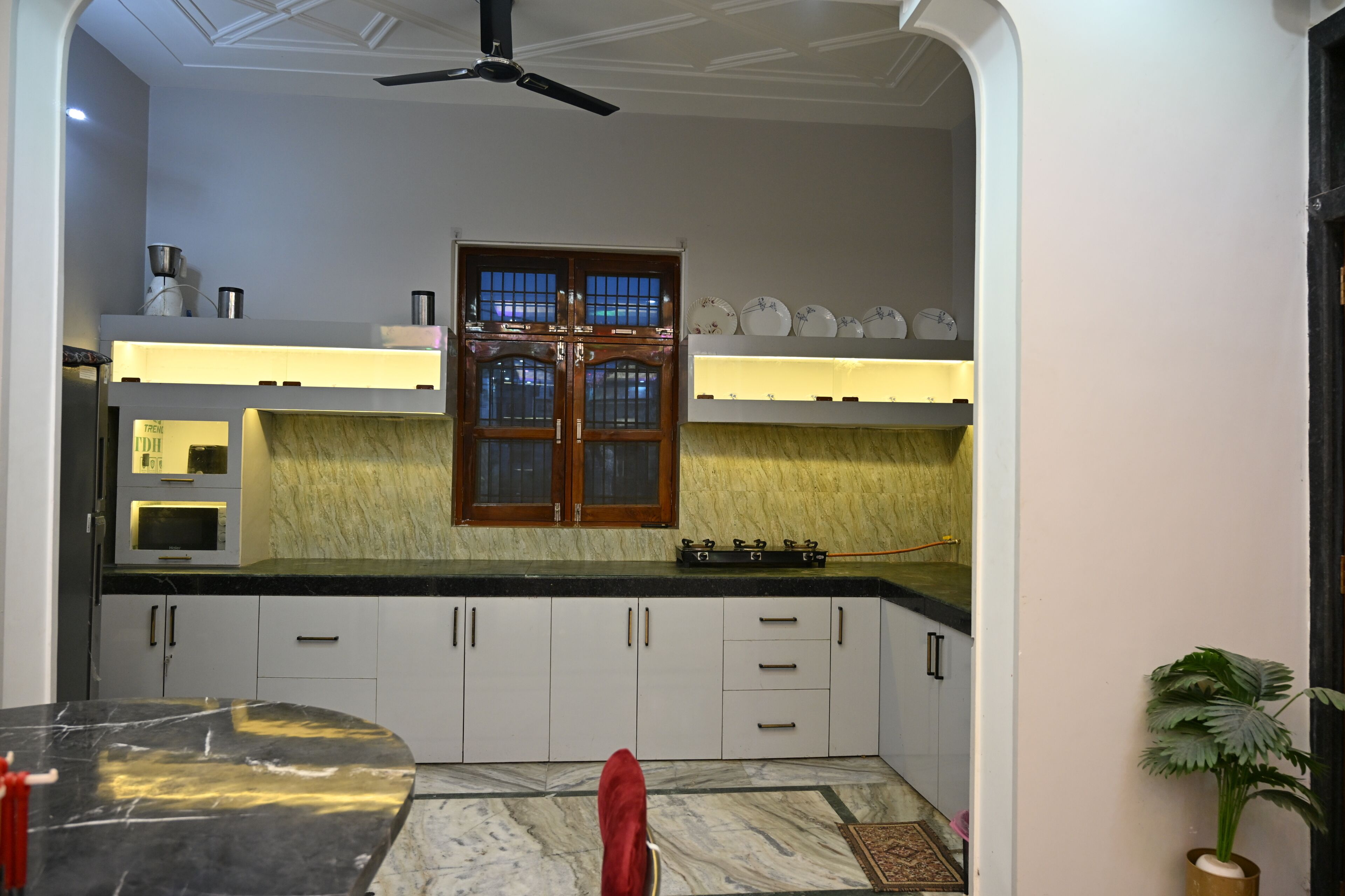 A kitchen with a central island, a window with a grid pattern, and a ceiling fan.