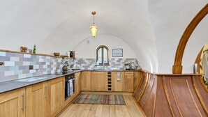 A kitchen with wooden cabinets, a tiled backsplash, and a wooden floor. - Beautiful  villa for 4 guests with WIFI and pets allowed (Bury St Edmunds)