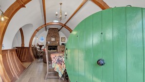 A room with a green door, wooden beams, a fireplace, and a bed with a floral bedspread. - Beautiful  villa for 4 guests with WIFI and pets allowed (Bury St Edmunds)