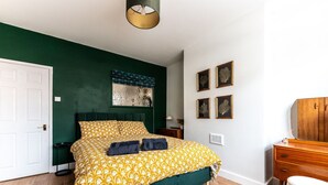 A bedroom with a bed, a dresser, a mirror, and a nightstand.
