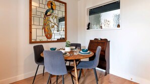 A dining area with a round table, four chairs, and a large stained glass artwork above the table.