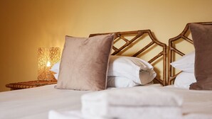 A neatly made bed with white linens and a brown pillow, a woven nightstand with a lamp, and a wooden headboard. - Stunning  villa for 10 guests with WIFI and TV (Belper)