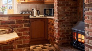 A kitchen with exposed wooden beams, a brick fireplace, and a checkered floor. - Stunning  villa for 10 guests with WIFI and TV (Belper)