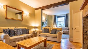 A cozy living room with two sofas, a wooden coffee table, and a fireplace.