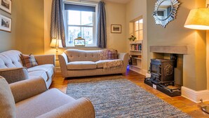 A cozy living room with a sofa, armchair, and a fireplace.