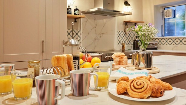 A breakfast setup with croissants, orange juice, and a French press coffee maker.