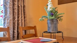 A wooden chair, a small table with a vase of flowers, and a red tray on a wooden table. - Beautiful  villa for 4 guests with WIFI, TV and pets allowed (Matlock)