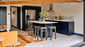 A modern kitchen with a central island, bar stools, and a refrigerator.