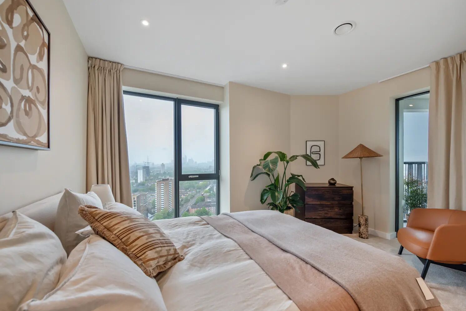 A modern bedroom with a large bed, a view of the city, and a balcony.