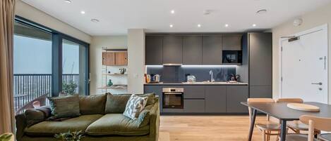 A modern apartment with a living area, kitchenette, and dining space.