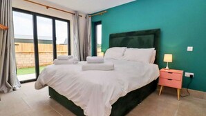 Une chambre à coucher avec un grand lit, une table de chevet, une lampe et une vue sur l’extérieur grâce à une porte coulissante.