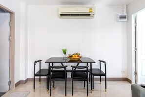Un comedor con una mesa y cuatro sillas, un aire acondicionado montado en la pared y un ventanal pequeño.