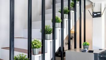 A modern staircase with black railings and potted plants.