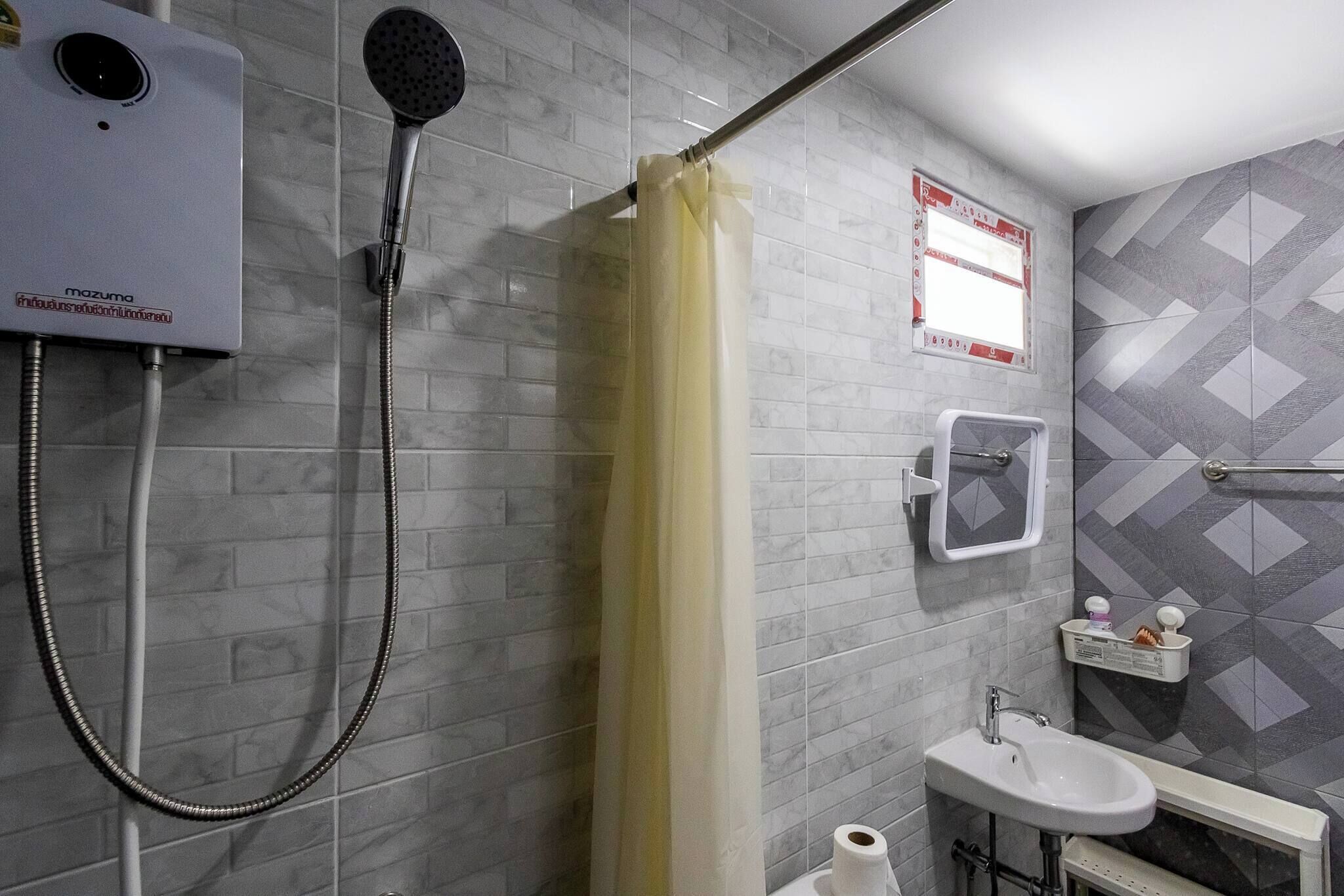 Un baño con ducha, inodoro, lavabo y espejo.