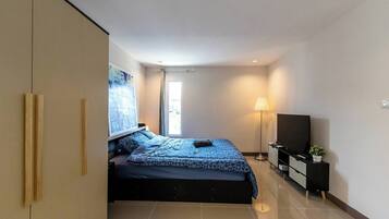 A modern bedroom with a bed, a TV, a lamp, and a large window.