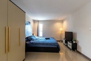 Un dormitorio moderno con cama, televisión, lámpara y un ventanal grande.
