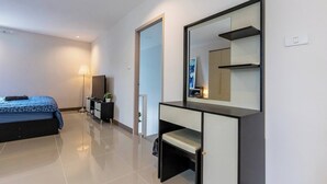 Una habitación de hotel moderna con cama, mesita de noche, lámpara y un espejo grande.