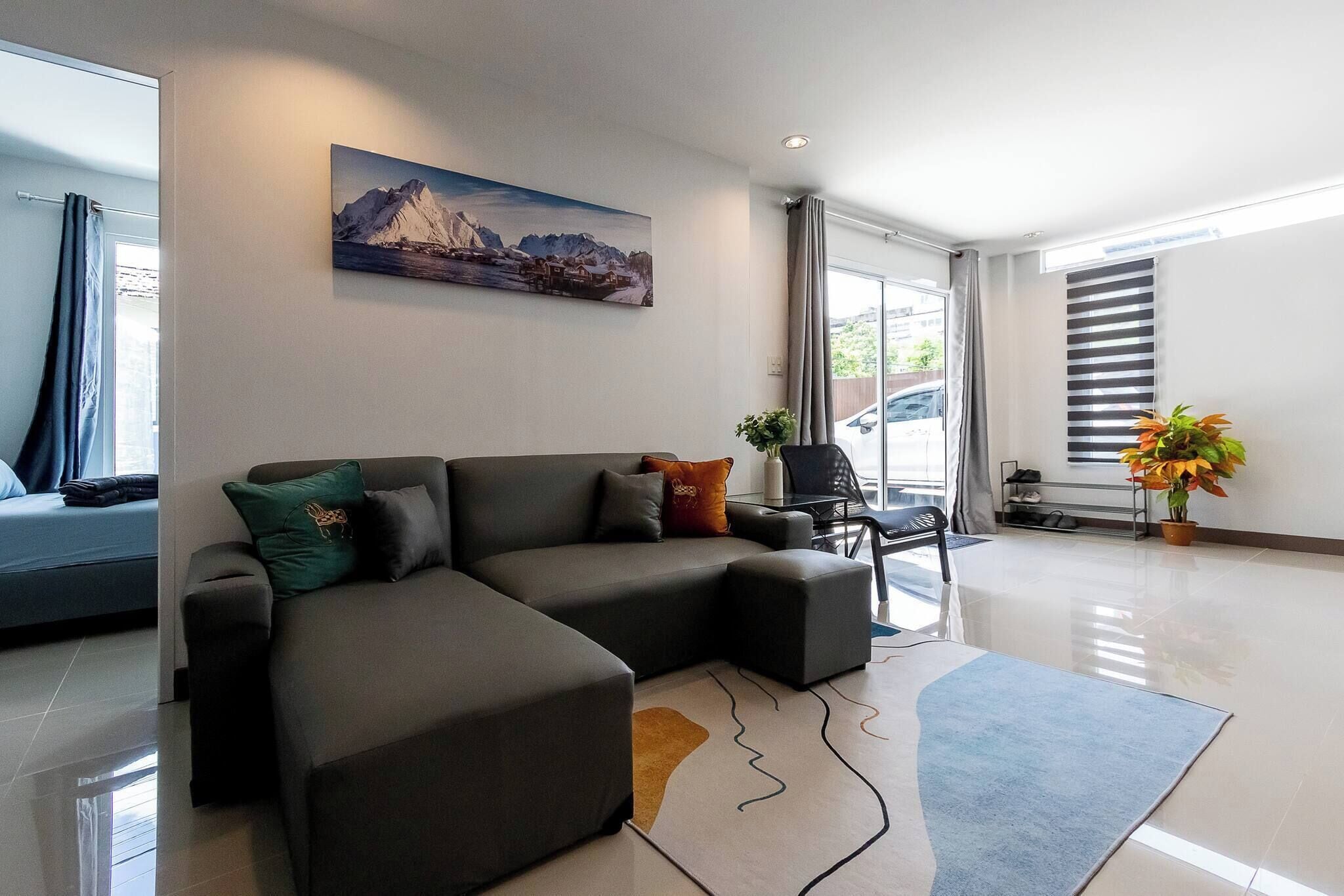 A modern living room with a sectional sofa, a painting, and a potted plant.