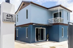 A modern two-story house with a balcony, a garage, and a driveway.