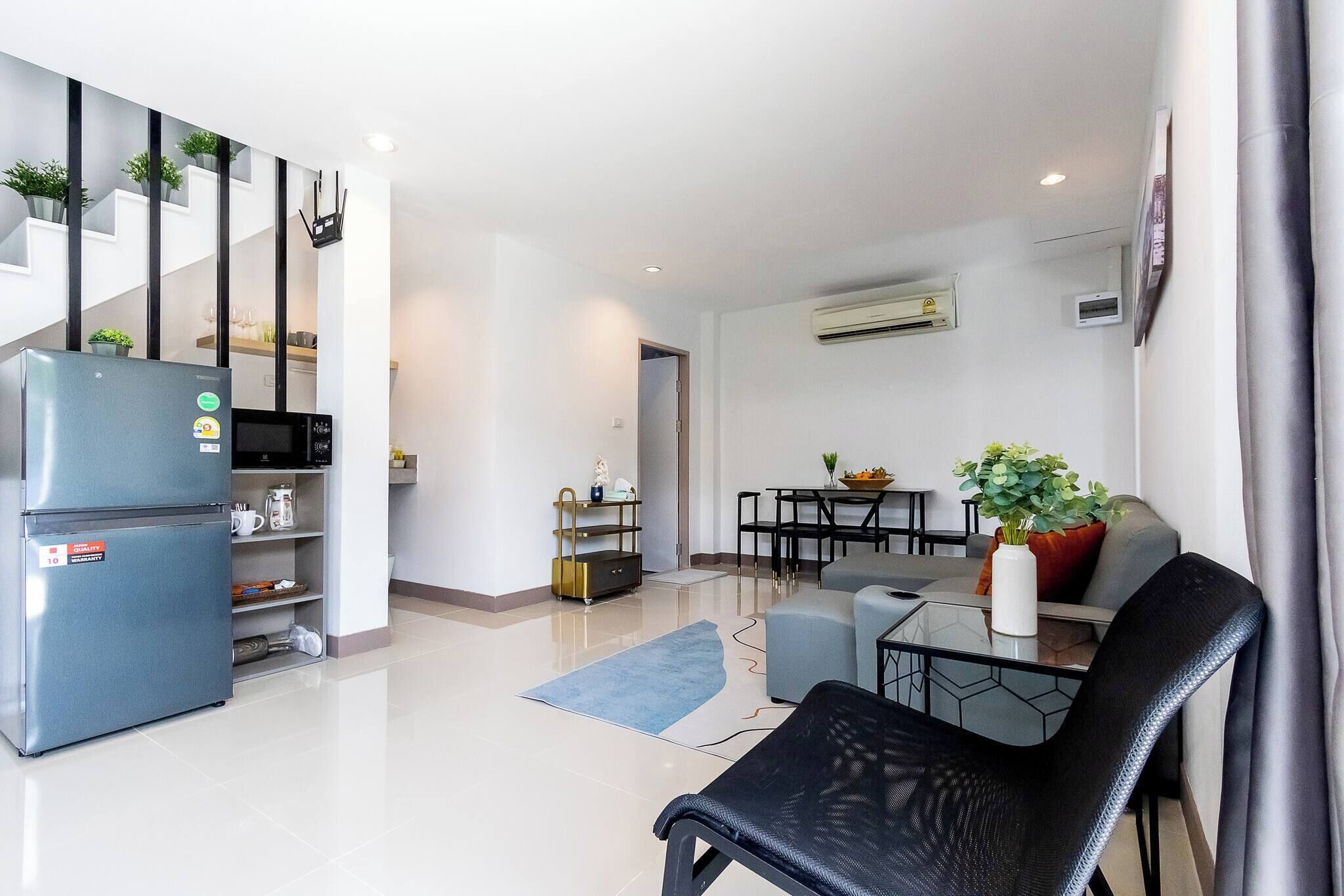 Un apartamento moderno con cocina, comedor y sala de estar. Incluye un refrigerador, una mesa de comedor y un sofá.