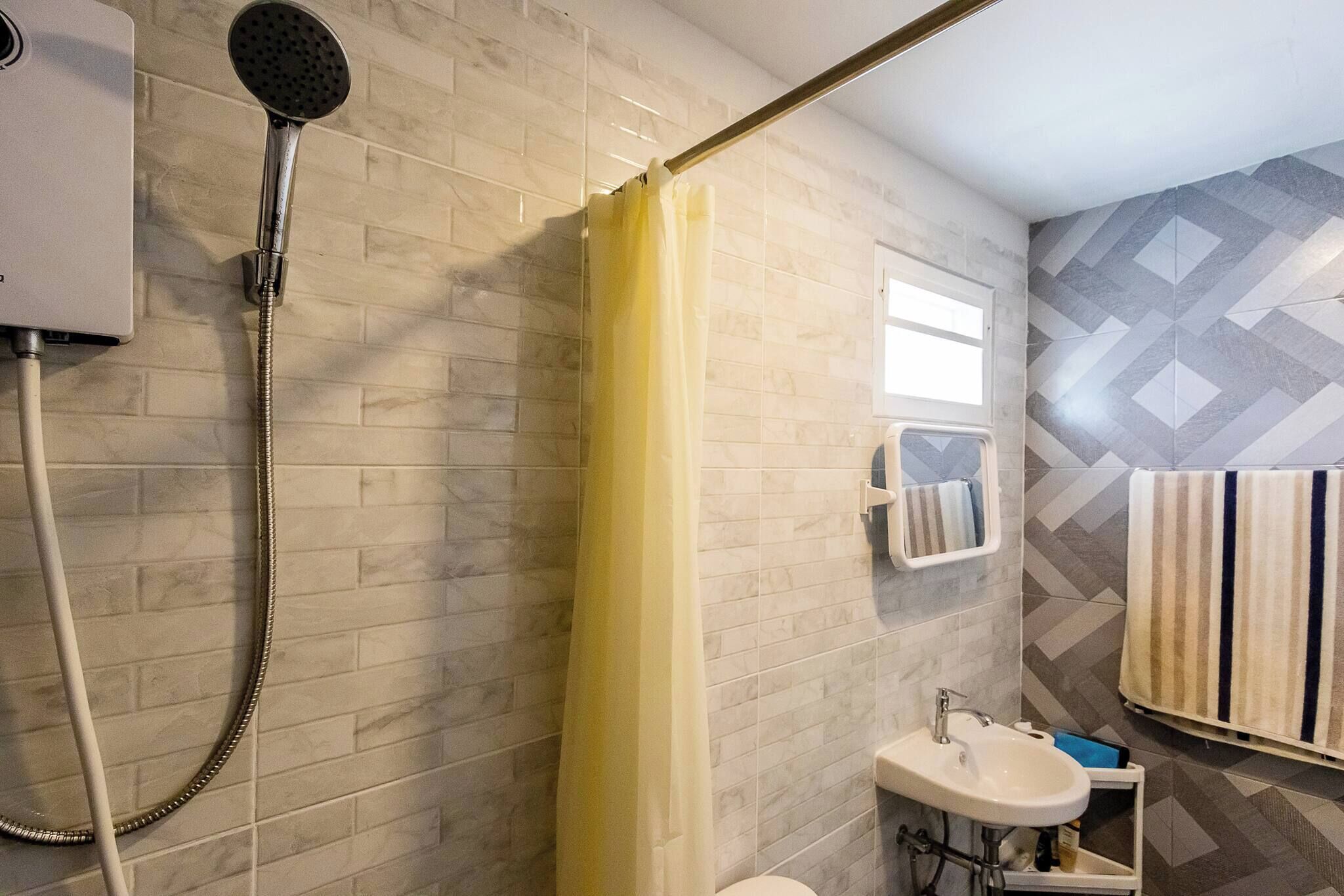 A bathroom with a shower, toilet, sink, and towel rack.