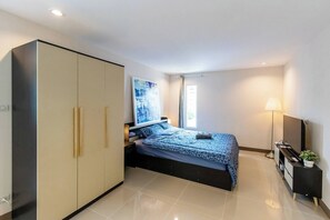 A bedroom with a bed, wardrobe, bedside table, lamp, and a painting on the wall. - Tiny House Srinakarin At Sri Bearing Station (Samut Prakan)