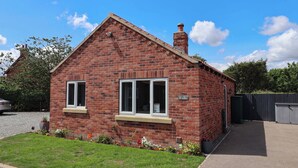 A red brick house with two windows and a chimney.